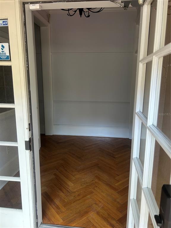 A view through an open doorway into a foyer with herringbone wood flooring and wainscoting — 5214 SW 91ST TERRACE, GAINESVILLE, FL