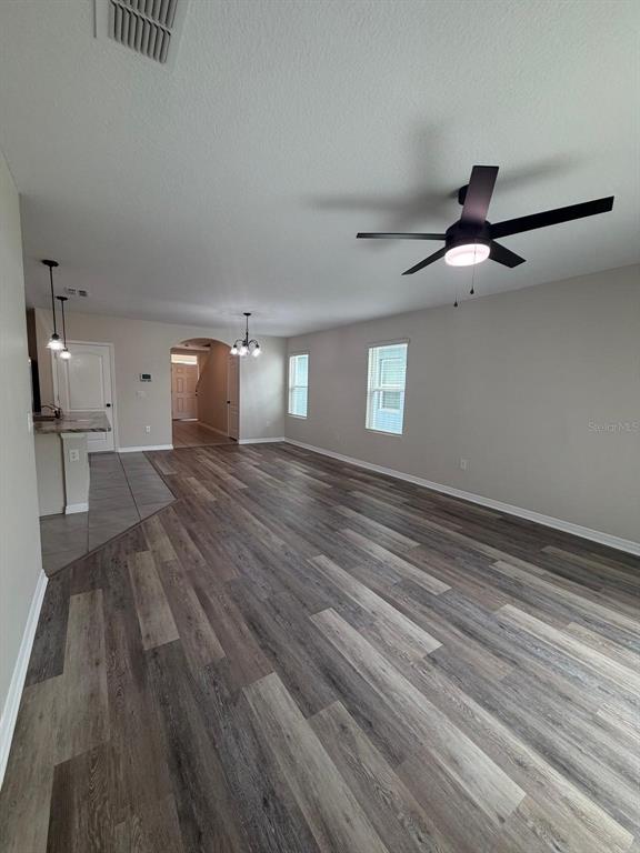 An open-concept living area features wood-look flooring, a ceiling fan, and a kitchen breakfast bar — 225 GINA LANE, DAVENPORT, FL