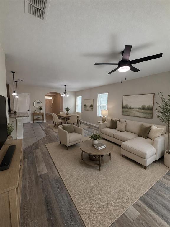 An open-concept living and dining area features light-colored furniture, a ceiling fan, and wood-look flooring — 225 GINA LANE, DAVENPORT, FL