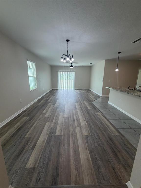 An open-concept living area features wood-look flooring, a kitchen island, and a sliding glass door — 225 GINA LANE, DAVENPORT, FL