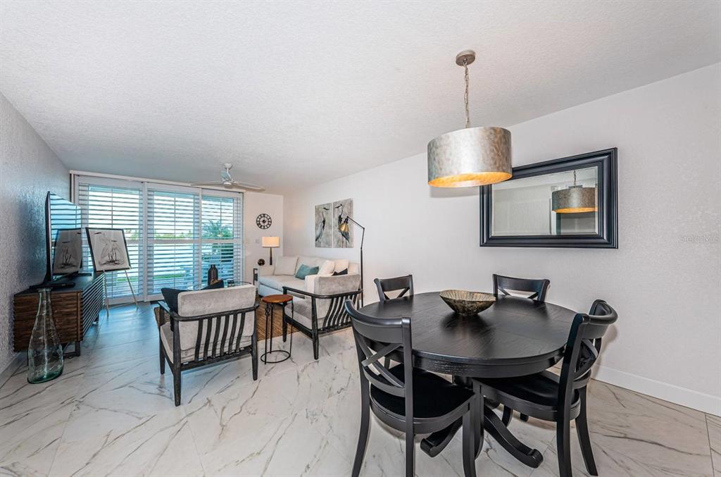 A dining area with a round table and a living room with marble-look flooring — 6083 BAHIA DEL MAR CIRCLE UNIT 159, ST PETERSBURG, FL
