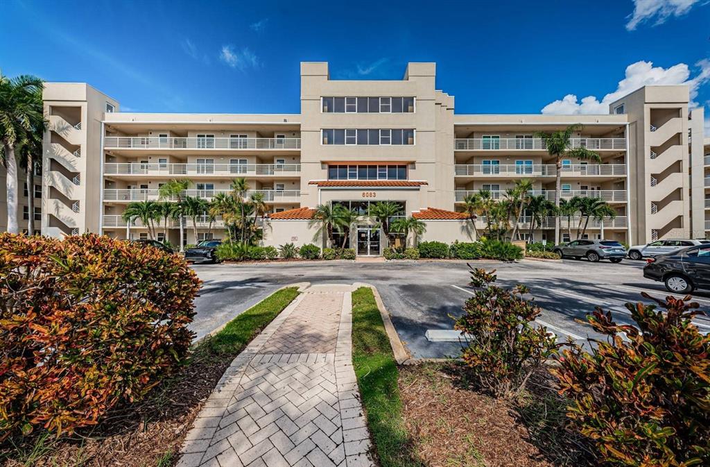 A multi-story apartment building with a paved walkway leading to the central entrance — 6083 BAHIA DEL MAR CIRCLE UNIT 159, ST PETERSBURG, FL