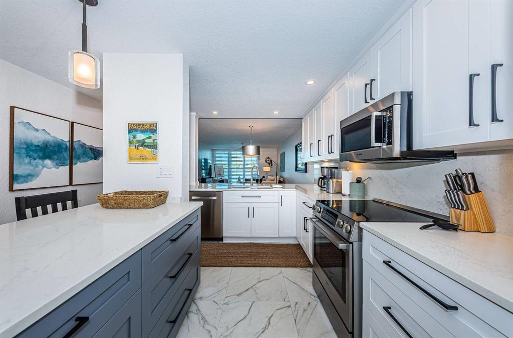 A modern kitchen features white upper cabinets, blue lower cabinets, and white marble-look countertops — 6083 BAHIA DEL MAR CIRCLE UNIT 159, ST PETERSBURG, FL