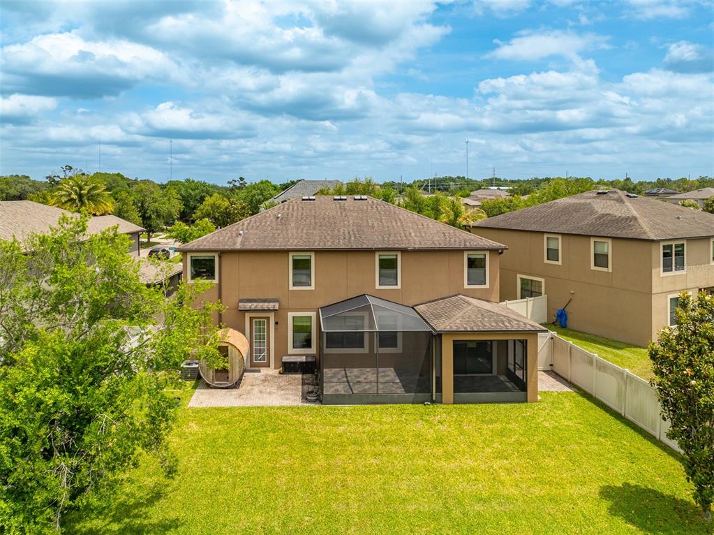 The rear exterior of a two-story house features a screened-in patio and a grassy yard — 11511 PALMETTO PINE STREET, RIVERVIEW, FL