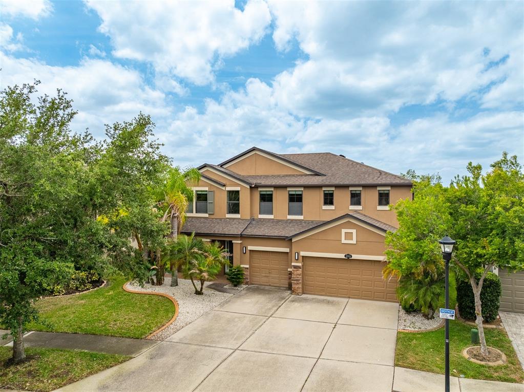 A two-story suburban house with a tan stucco exterior, brown roof, and three-car garage — 11511 PALMETTO PINE STREET, RIVERVIEW, FL