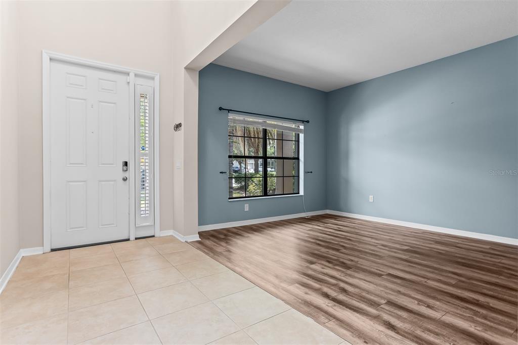 An entryway with tile flooring leads into a living area featuring wood-look floors and blue walls — 11511 PALMETTO PINE STREET, RIVERVIEW, FL