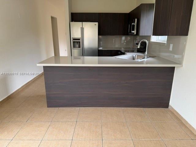 A kitchen features dark wood cabinets, stainless steel appliances, and a white countertop island — 706 SE 14th Ave, Homestead FL 33033, HOMESTEAD, FL