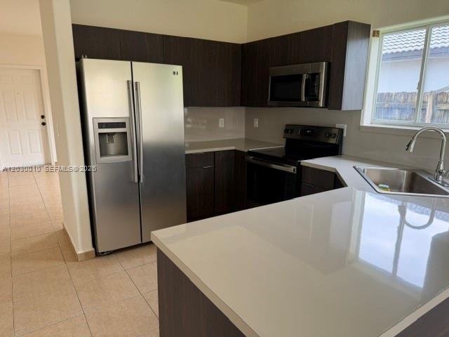 A kitchen features dark wood cabinets, stainless steel appliances, and a white quartz countertop — 706 SE 14th Ave, Homestead FL 33033, HOMESTEAD, FL