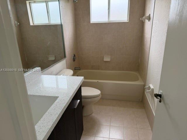 A bathroom features a white vanity, a toilet, and a bathtub with beige wall tiles — 706 SE 14th Ave, Homestead FL 33033, HOMESTEAD, FL