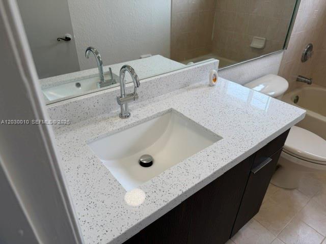 A bathroom features a white speckled countertop, a dark vanity cabinet, and a wall mirror — 706 SE 14th Ave, Homestead FL 33033, HOMESTEAD, FL