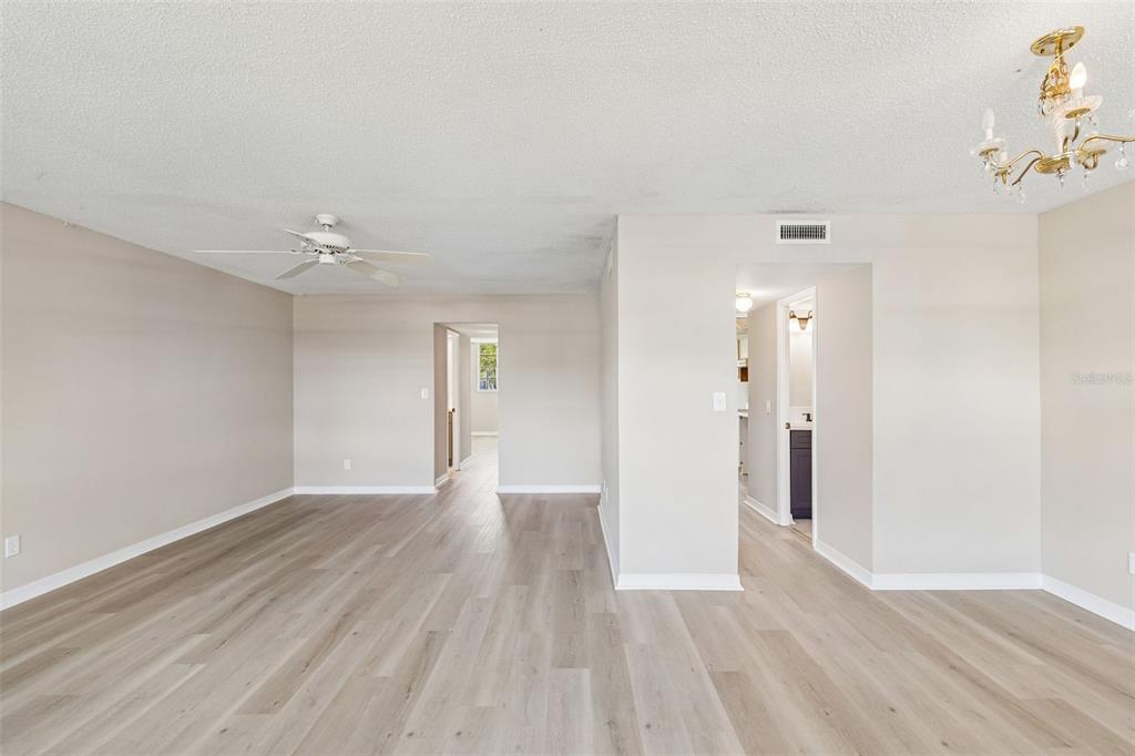 An open-concept living area features light wood-look flooring, a ceiling fan, and a chandelier — 4705 1ST STREET NE UNIT 138, ST PETERSBURG, FL