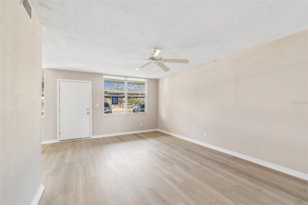 An empty room with light-colored walls, wood-look flooring, a ceiling fan, and a white door — 4705 1ST STREET NE UNIT 138, ST PETERSBURG, FL
