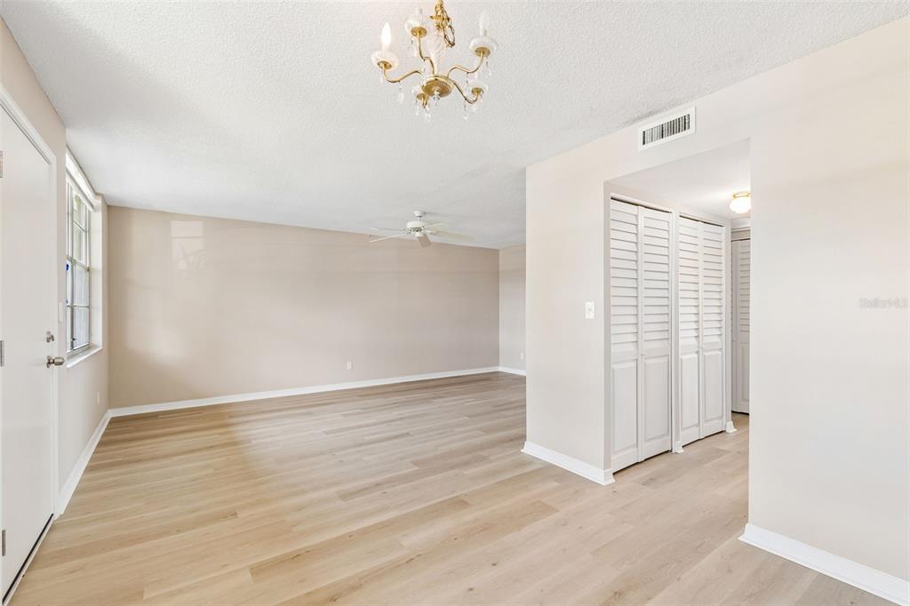 An empty living room features light wood-look flooring, a ceiling fan, and white louvered closet doors — 4705 1ST STREET NE UNIT 138, ST PETERSBURG, FL