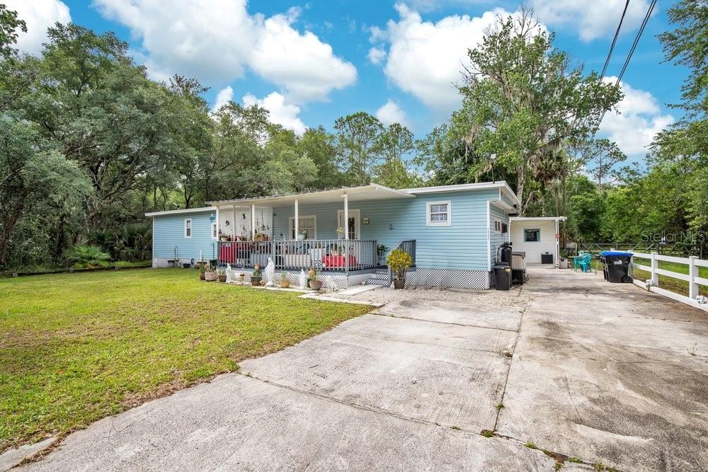 A light blue manufactured home with a front porch and a concrete driveway — 18222 LYNBROOK ROAD, ORLANDO, FL