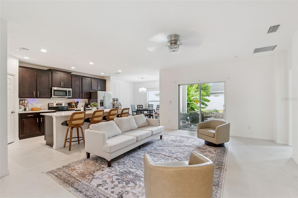 An open-concept living room and kitchen featuring dark cabinetry, a white island, and sliding glass doors — 1055 CHASE AUSTIN WAY, SANFORD, FL