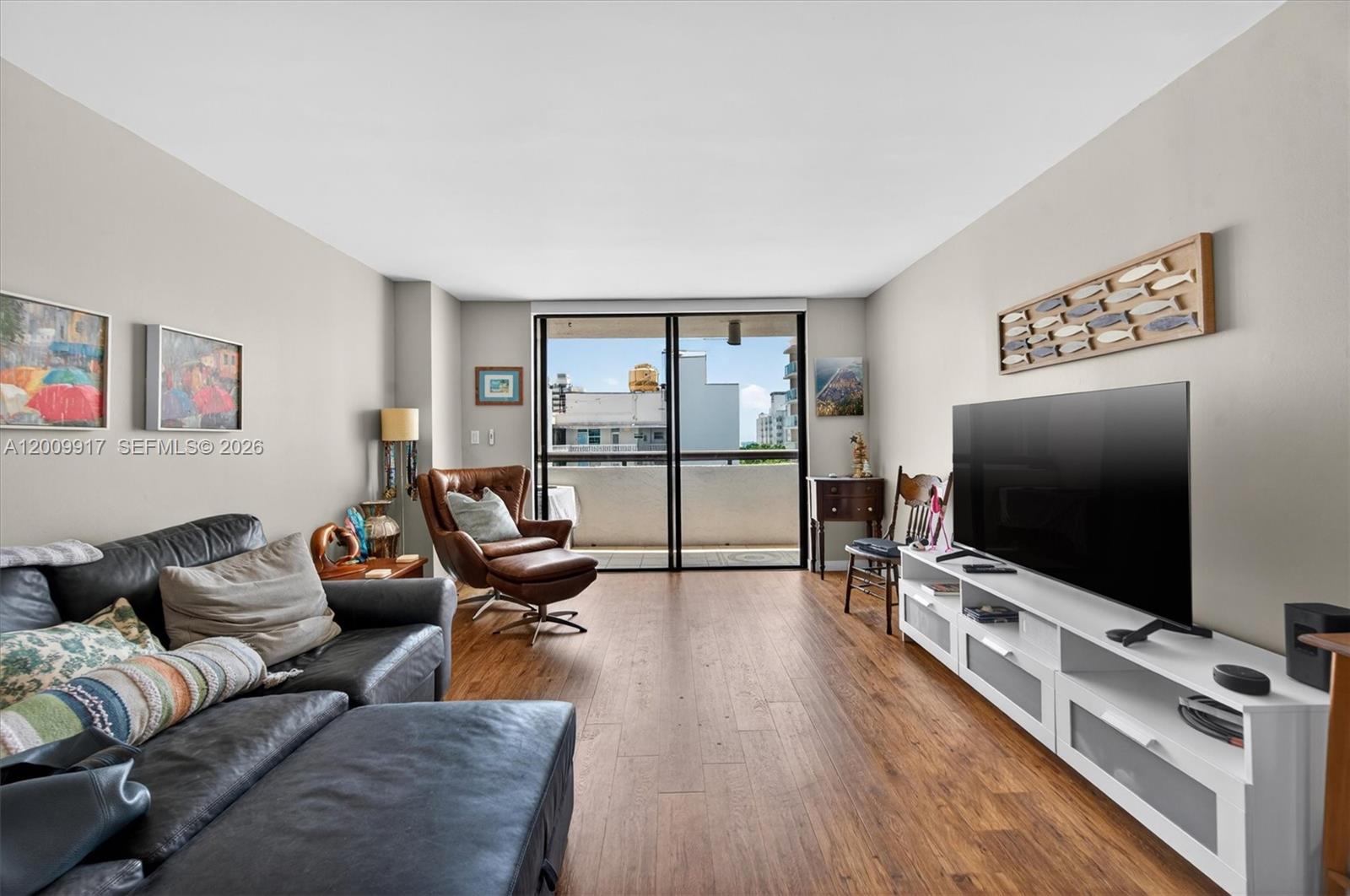 A living room features a dark leather sectional, a brown armchair, and a white media console — 1775 Washington Ave # 7B, Miami Beach FL 33139, MIAMI BEACH, FL