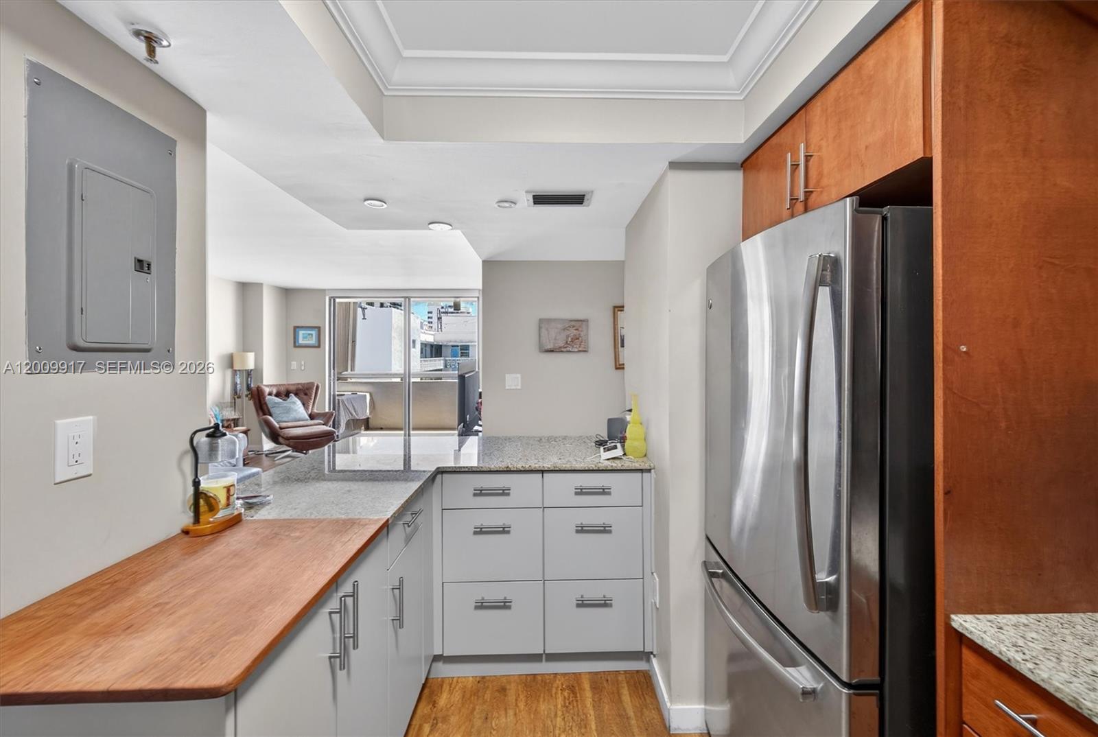 A kitchen features gray cabinets, a wooden countertop, and a stainless steel refrigerator — 1775 Washington Ave # 7B, Miami Beach FL 33139, MIAMI BEACH, FL