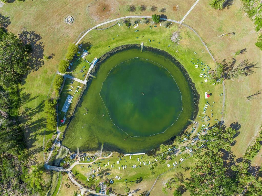 An aerial view shows a circular swimming lake surrounded by a grassy park and trees — 1024 HOFFER STREET, PORT CHARLOTTE, FL