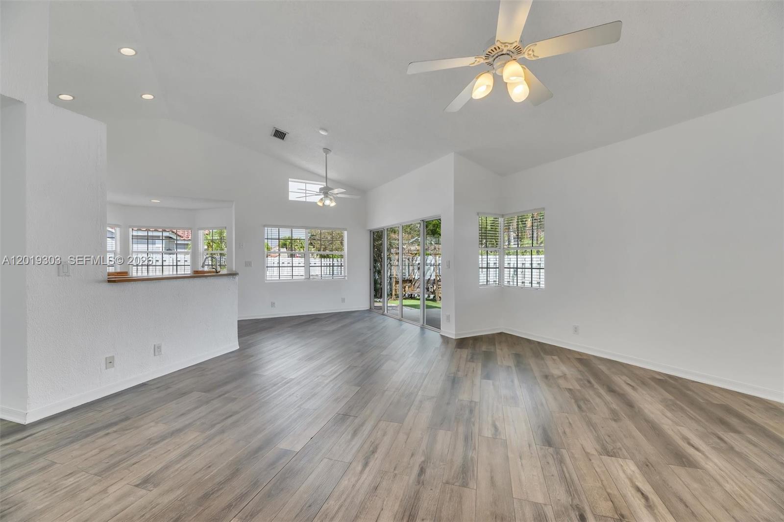 An empty living area features white walls, vaulted ceilings, and wood-look flooring — 535 Somerset Way, Weston FL 33326, WESTON, FL