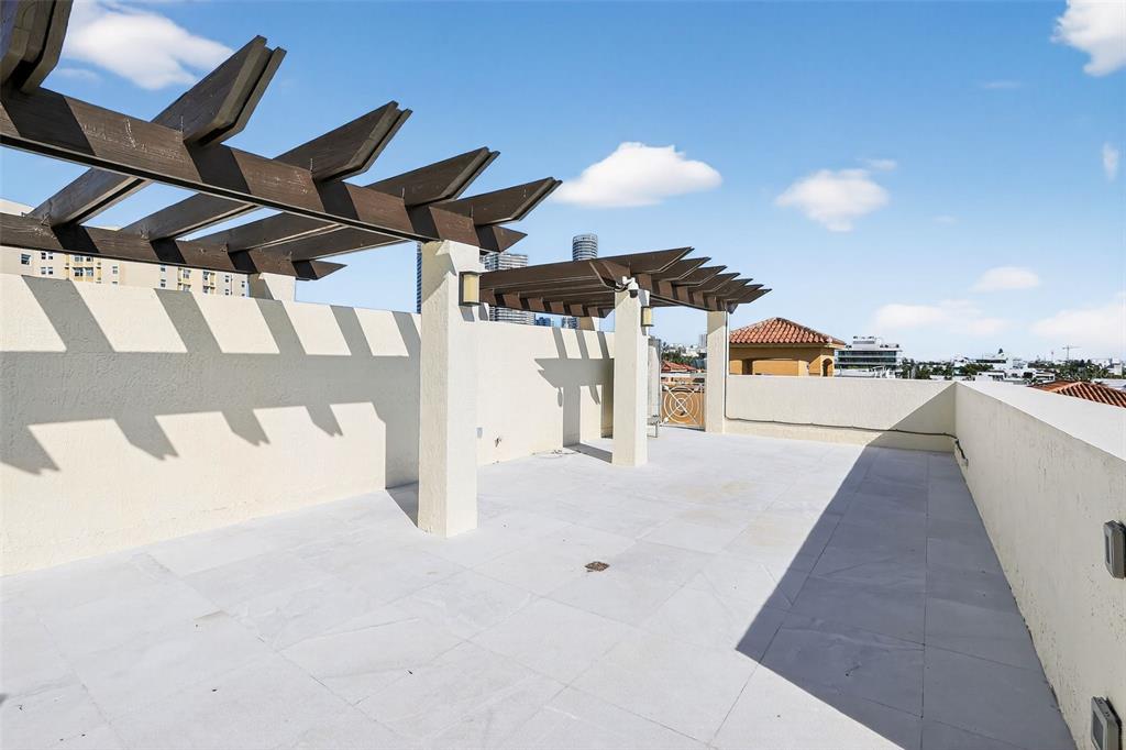 A rooftop terrace features a wooden pergola, light-colored tile flooring, and surrounding stucco walls — 120 JEFFERSON AVENUE UNIT 12009, MIAMI BEACH, FL