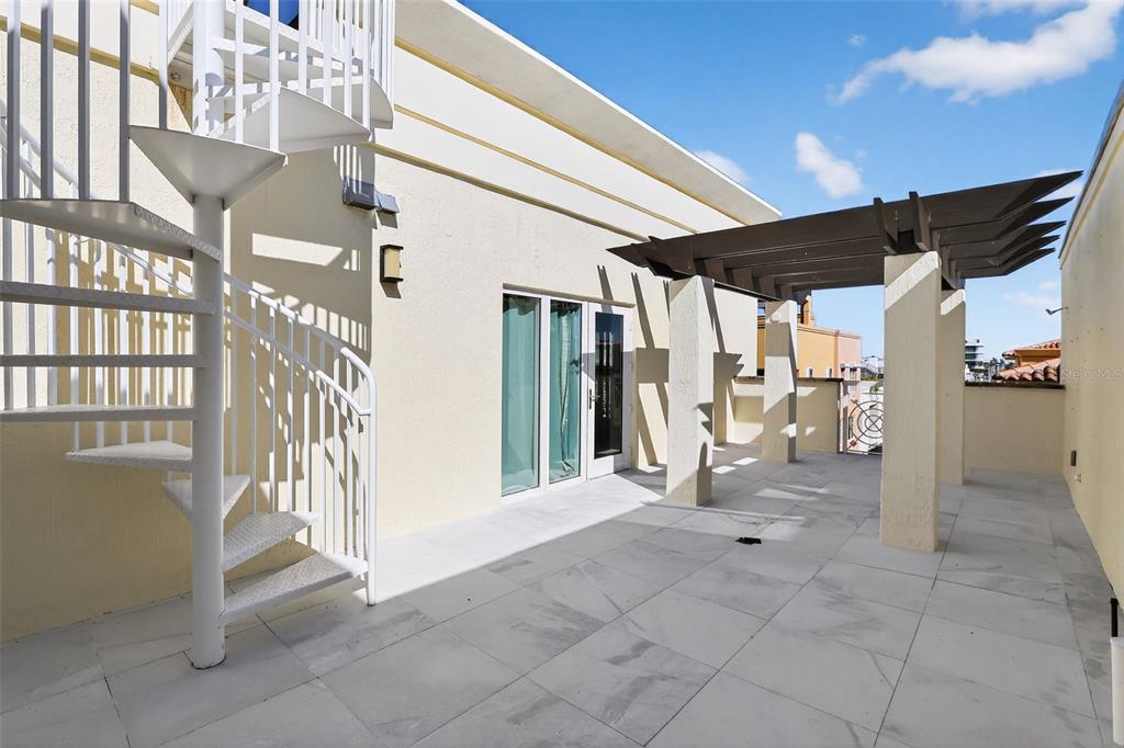 A rooftop terrace features a white spiral staircase, a pergola, and light-colored tiled flooring — 120 JEFFERSON AVENUE UNIT 12009, MIAMI BEACH, FL