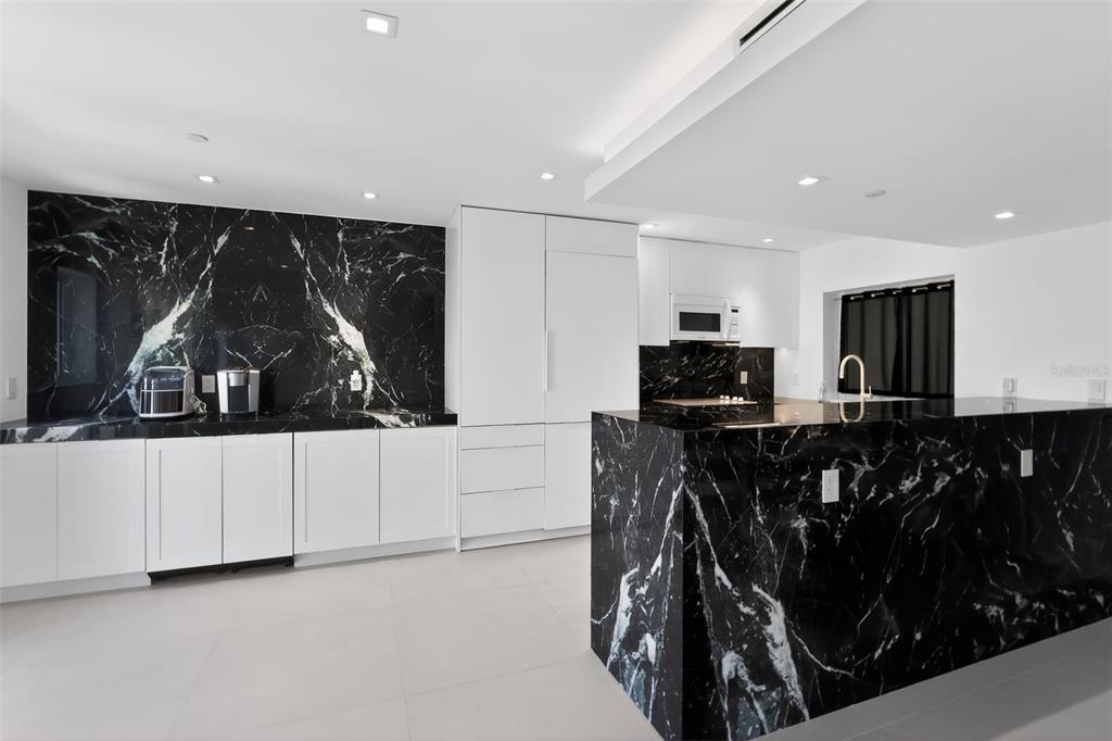A modern kitchen features white cabinets, black marble countertops, and a matching black marble island — 120 JEFFERSON AVENUE UNIT 12009, MIAMI BEACH, FL