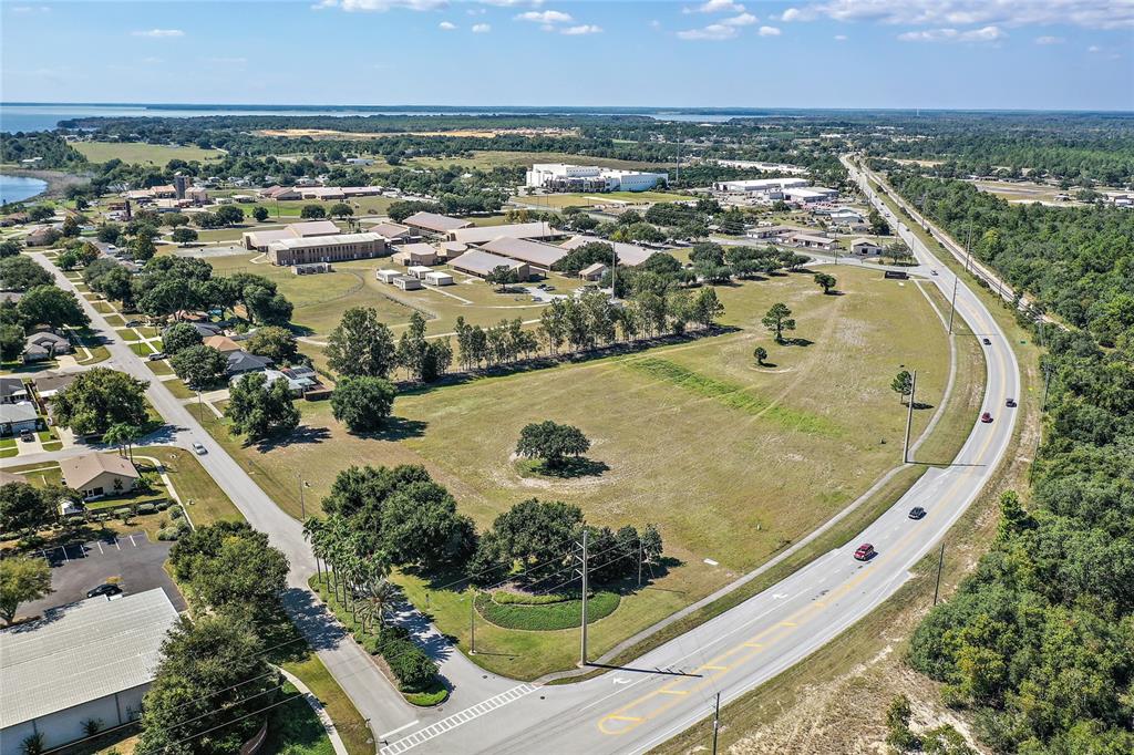An aerial view shows a large grassy lot bordered by a road and nearby buildings — CR 561 & LANE PARK CUTOFF, TAVARES, FL