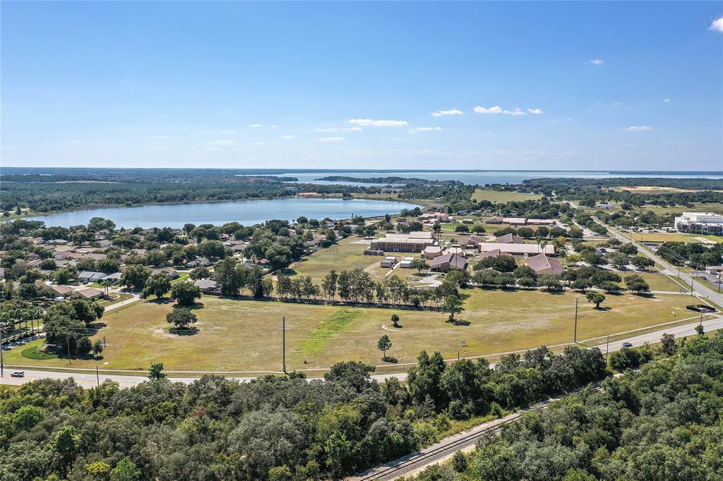 An aerial view shows a large grassy lot near a lake and a school campus — CR 561 & LANE PARK CUTOFF, TAVARES, FL