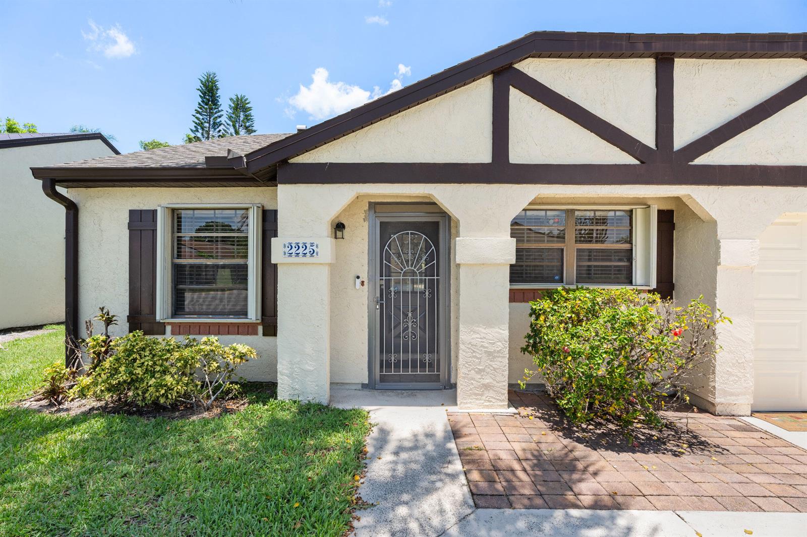 A single-story house exterior features stucco walls, brown trim, a front door, and landscaping — 2225 SE Barrington Street, FL 34952, FL
