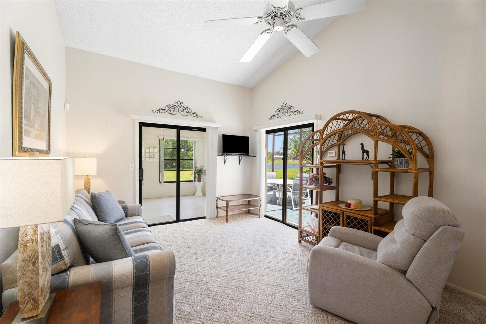 A living room features a vaulted ceiling, carpeted floors, and sliding glass doors to a patio — 2225 SE Barrington Street, FL 34952, FL