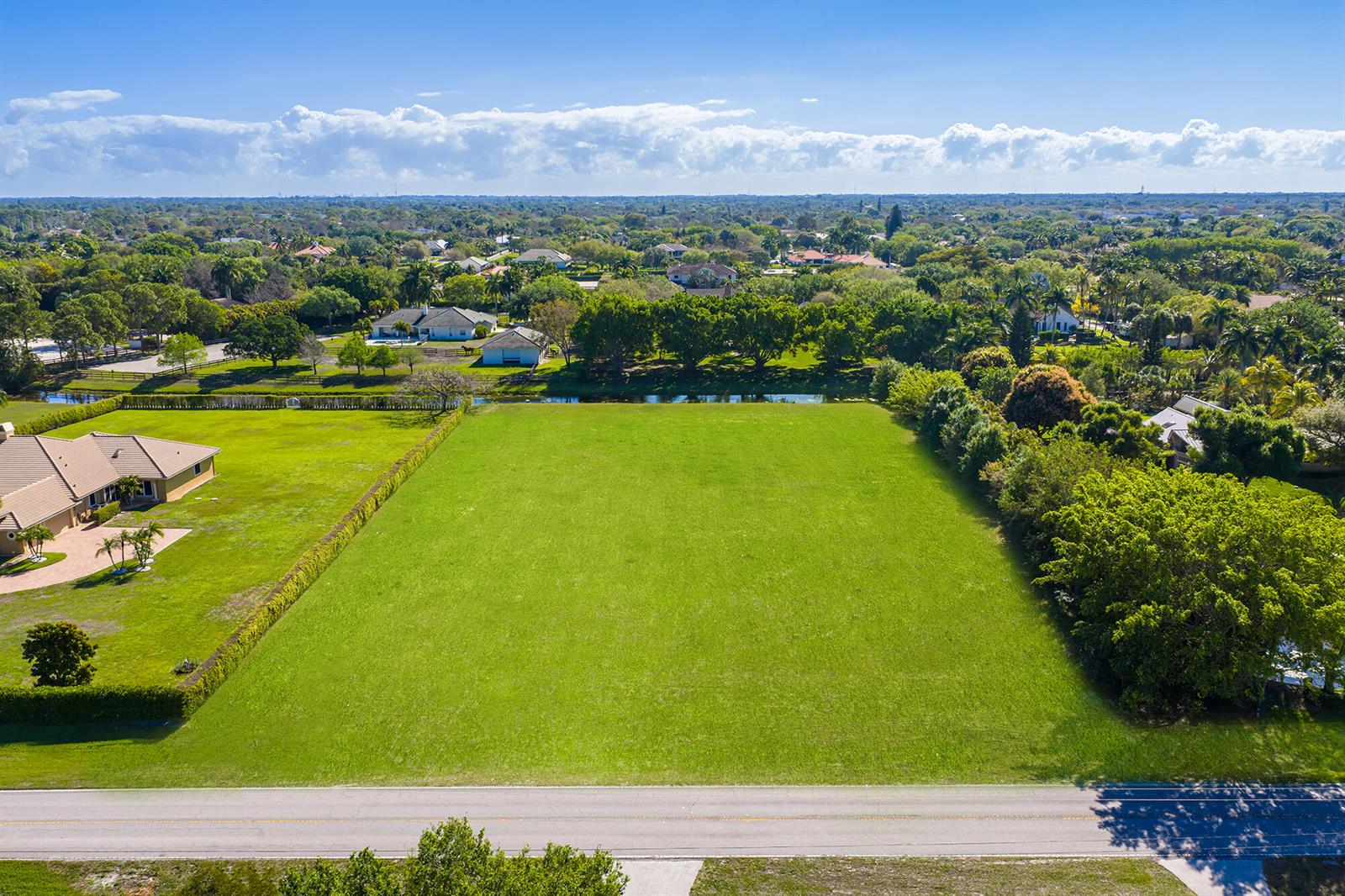 An aerial view shows a large, vacant rectangular grass lot bordered by trees and houses — 14404 Wellington Trace, Wellington FL 33414, WELLINGTON, FL