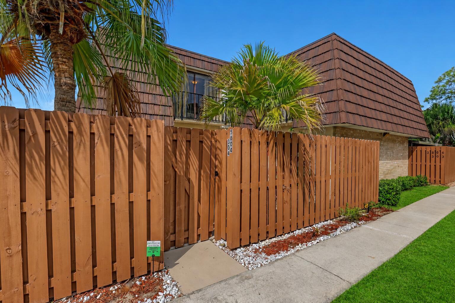 A brown wooden fence surrounds the front entrance of a two-story building with a mansard roof — 5808 SE Riverboat Drive # 304, Stuart FL 34997, STUART, FL