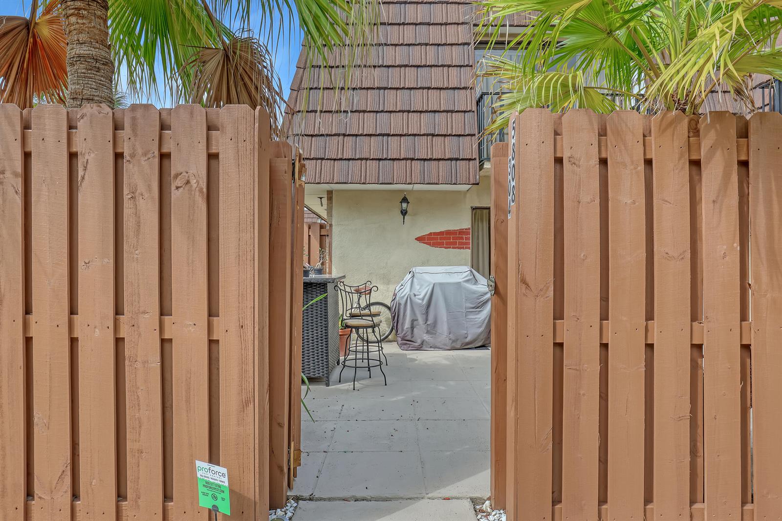 A wooden gate opens to a patio featuring a covered grill and bar stools — 5808 SE Riverboat Drive # 304, Stuart FL 34997, STUART, FL
