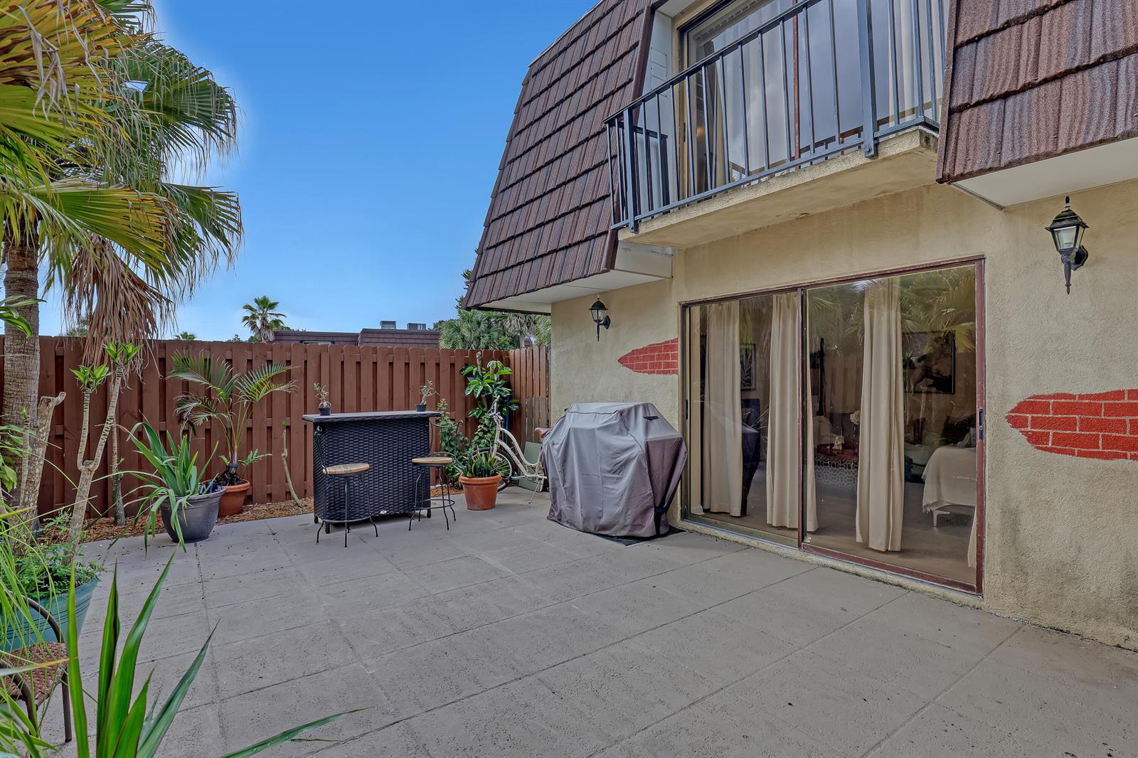 A patio with a grill, bar set, and potted plants sits outside a two-story building — 5808 SE Riverboat Drive # 304, Stuart FL 34997, STUART, FL