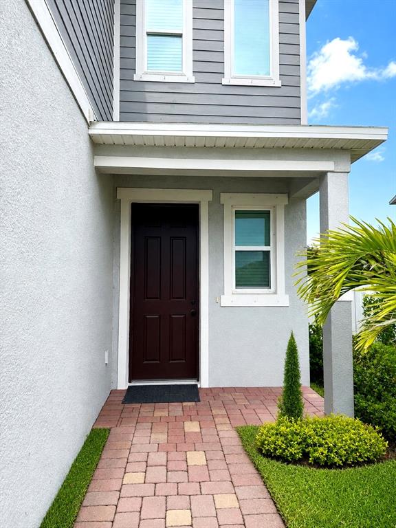 A front entryway features a dark brown door, a paver walkway, and gray siding — 2726 89TH STREET CIRCLE E, PALMETTO, FL