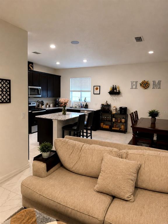 An open-concept kitchen with dark cabinets and a granite island overlooks a living area — 2726 89TH STREET CIRCLE E, PALMETTO, FL