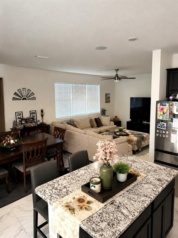 An open-concept kitchen and living area features a granite-topped island and a sectional sofa — 2726 89TH STREET CIRCLE E, PALMETTO, FL