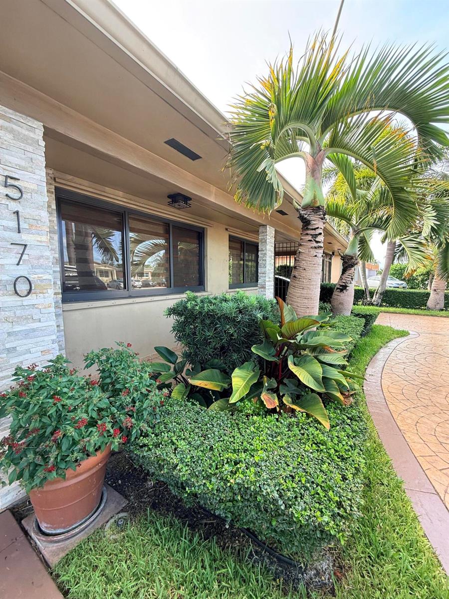 A low-angle exterior view shows a house facade with stone siding, windows, and landscaping — 5170 Palm Avenue, Hialeah FL 33012, HIALEAH, FL