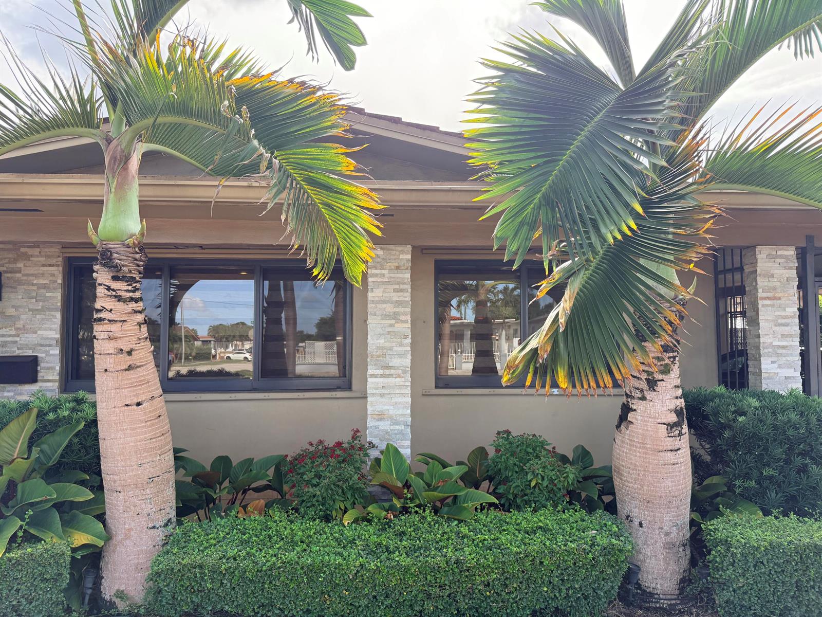 The exterior of a house features two palm trees flanking windows and stone-accented pillars — 5170 Palm Avenue, Hialeah FL 33012, HIALEAH, FL