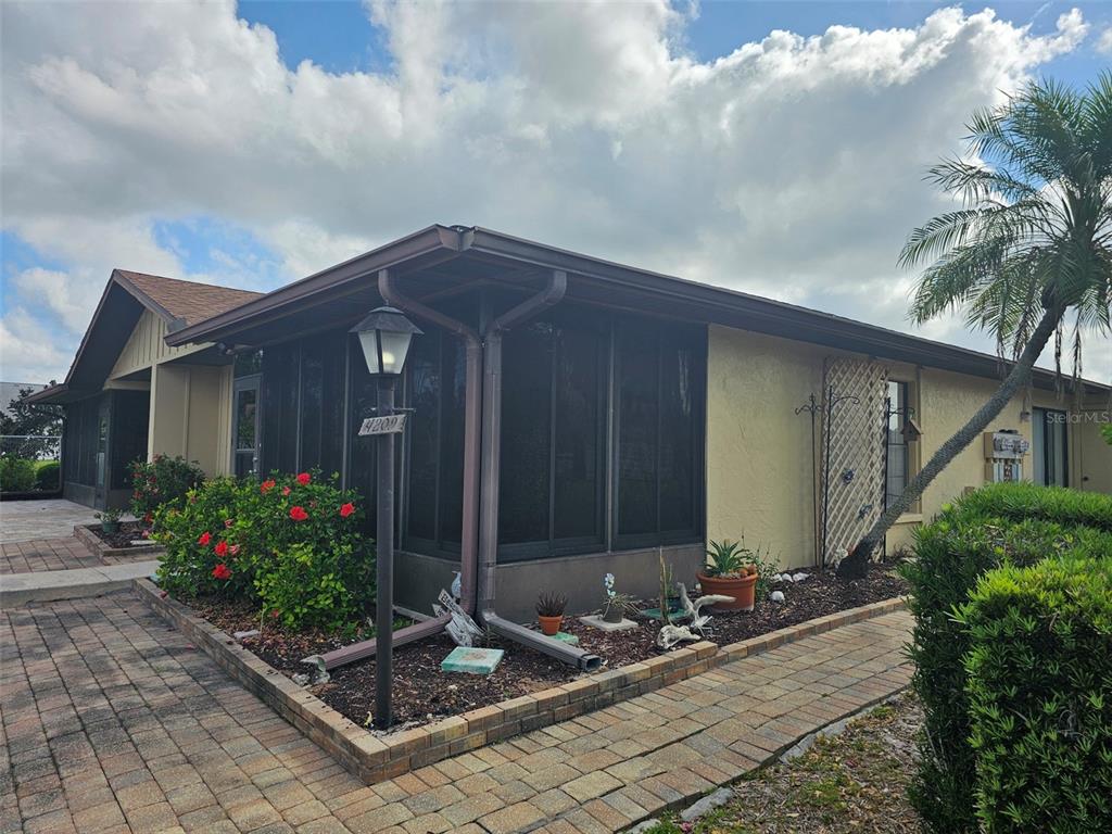 A single-story house with a screened-in porch, brick paver walkway, and a palm tree — 4209 66TH STREET CIRCLE W, BRADENTON, FL