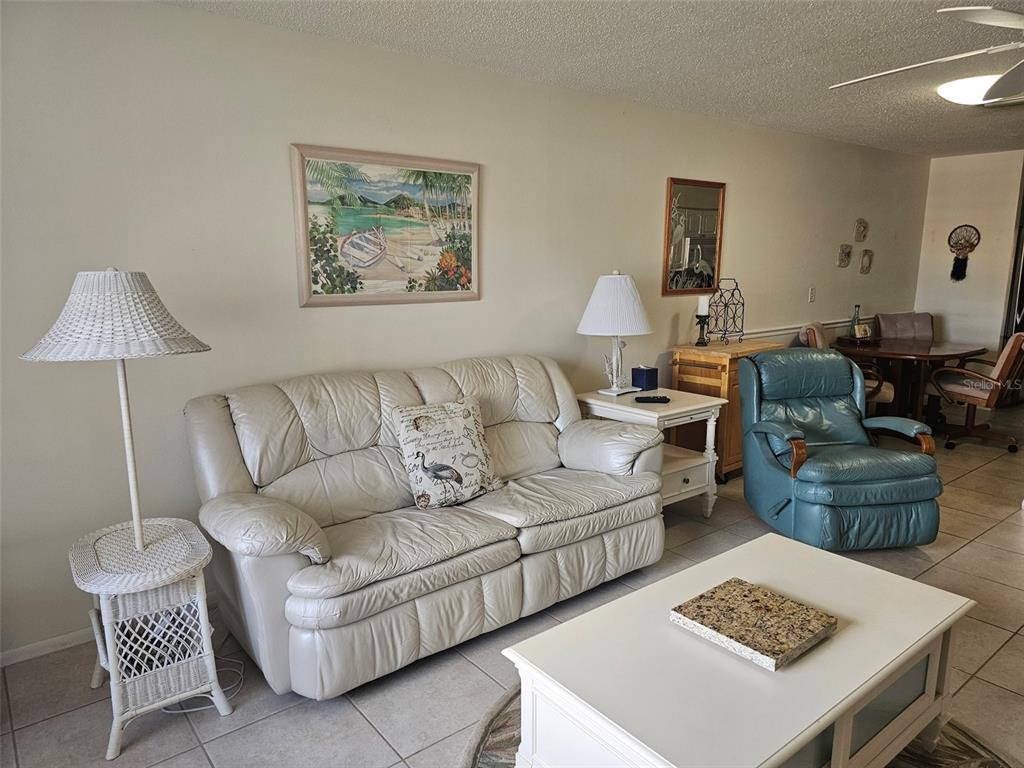 A living room features a white leather sofa, a blue recliner, and a white coffee table — 4209 66TH STREET CIRCLE W, BRADENTON, FL