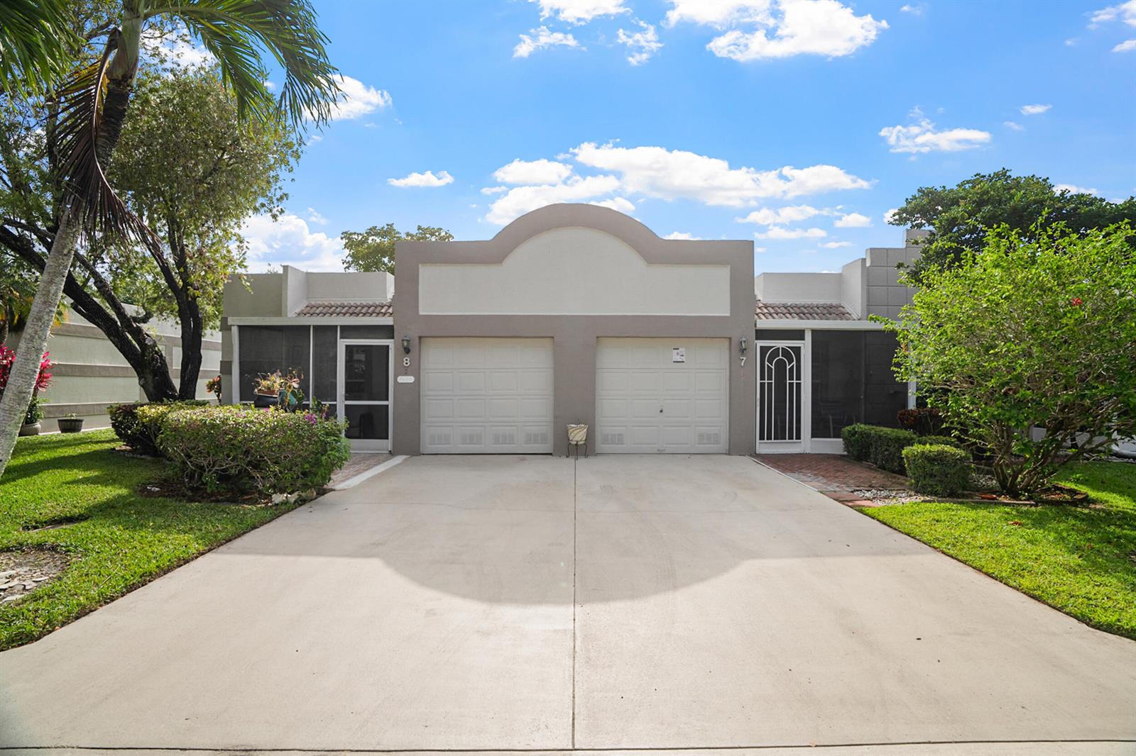 A duplex home features two garage doors, screened entryways, and a shared concrete driveway — 18900 Stewart Circle # 7, Boca Raton FL 33496, BOCA RATON, FL