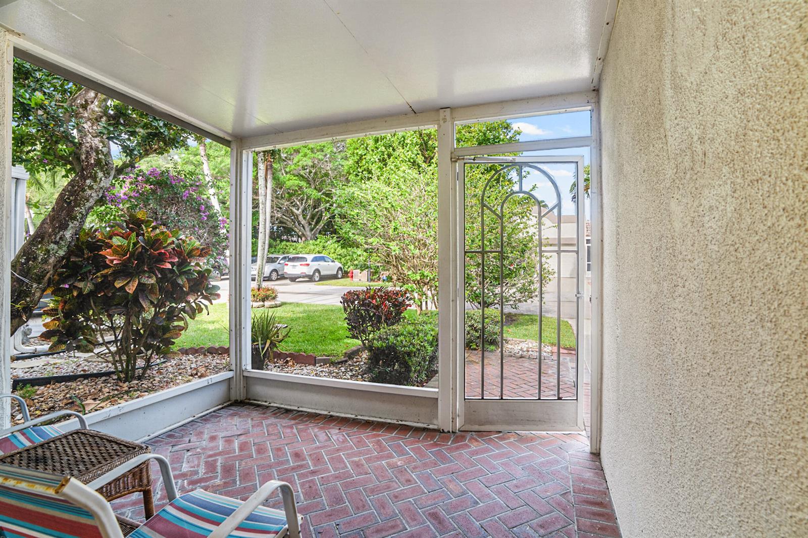 A screened-in porch with a brick floor, white metal framing, and a decorative storm door — 18900 Stewart Circle # 7, Boca Raton FL 33496, BOCA RATON, FL