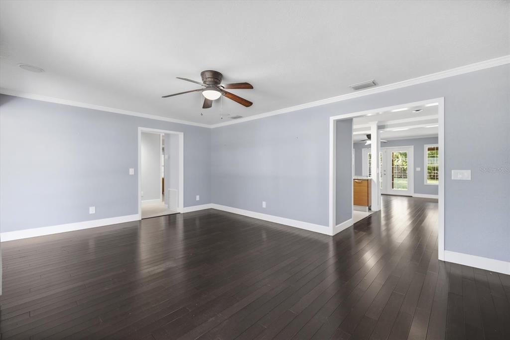 A spacious living room with light blue walls, dark hardwood floors, and a ceiling fan — 1894 LOMA LINDA STREET, SARASOTA, FL