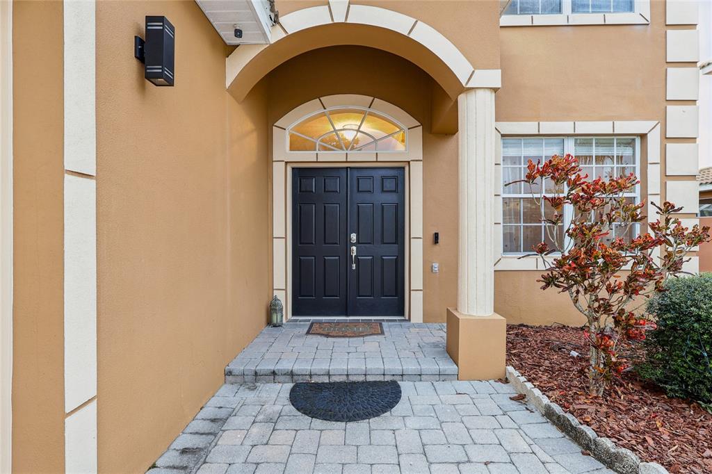 A tan house exterior features a double front door under an arched entryway with columns — 215 VISTA DRIVE, DAVENPORT, FL