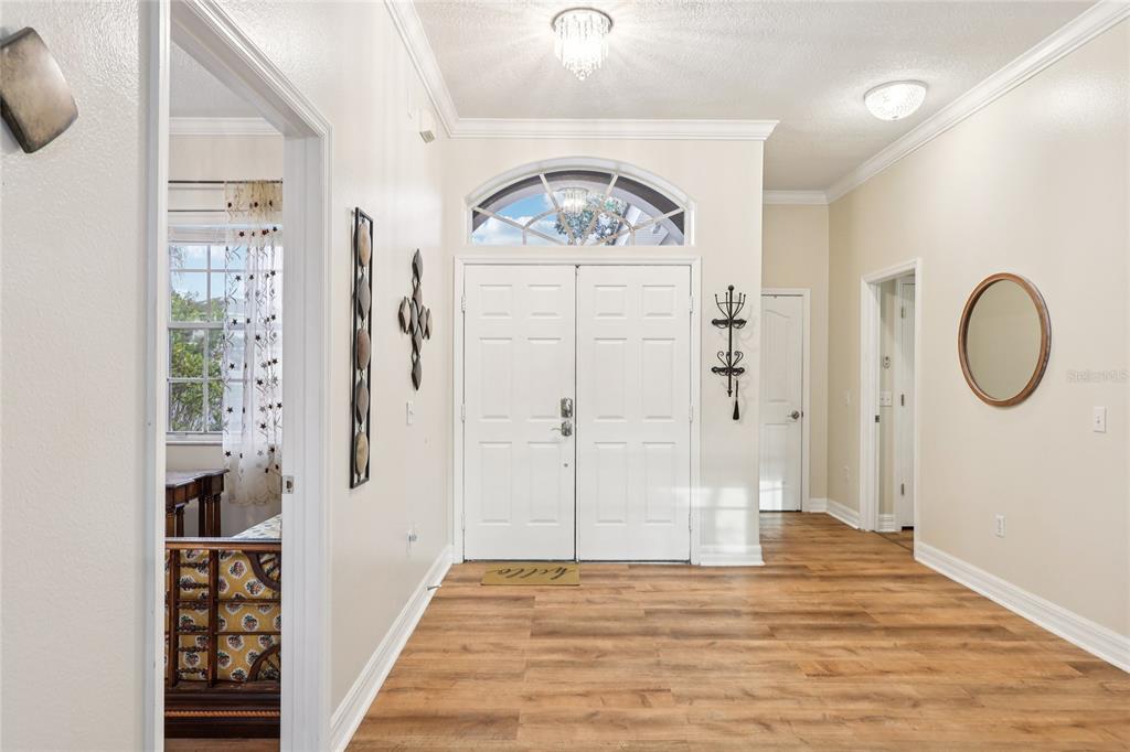A bright entryway features white double doors, light wood-look flooring, and a crystal chandelier — 215 VISTA DRIVE, DAVENPORT, FL