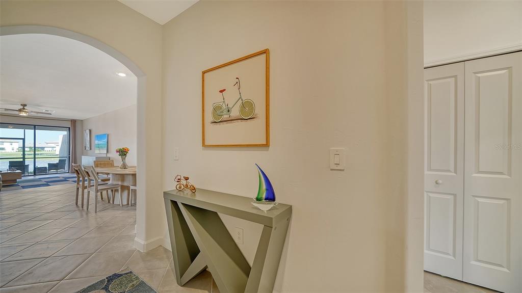 A foyer features a console table, bicycle wall art, and an arched entryway to a living area — 15721 SUNNY DAY DRIVE, BRADENTON, FL