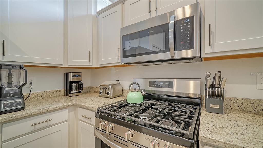 A kitchen features white cabinets, granite countertops, and stainless steel appliances including a gas range — 15721 SUNNY DAY DRIVE, BRADENTON, FL
