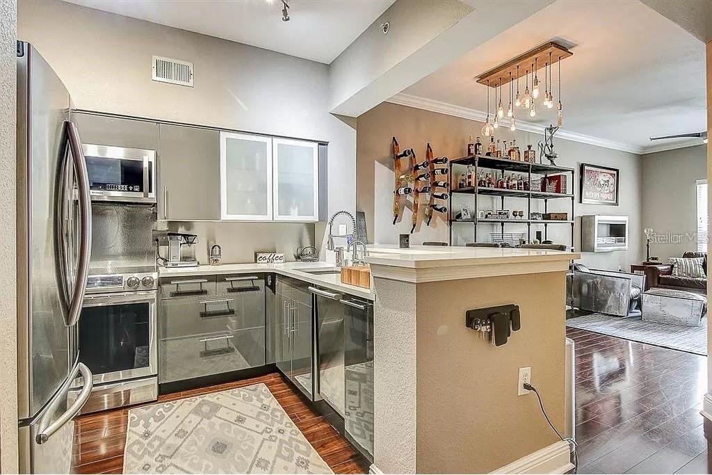 A modern kitchen features gray cabinets, stainless steel appliances, and an open bar area — 100 4TH AVENUE S UNIT 205, ST PETERSBURG, FL