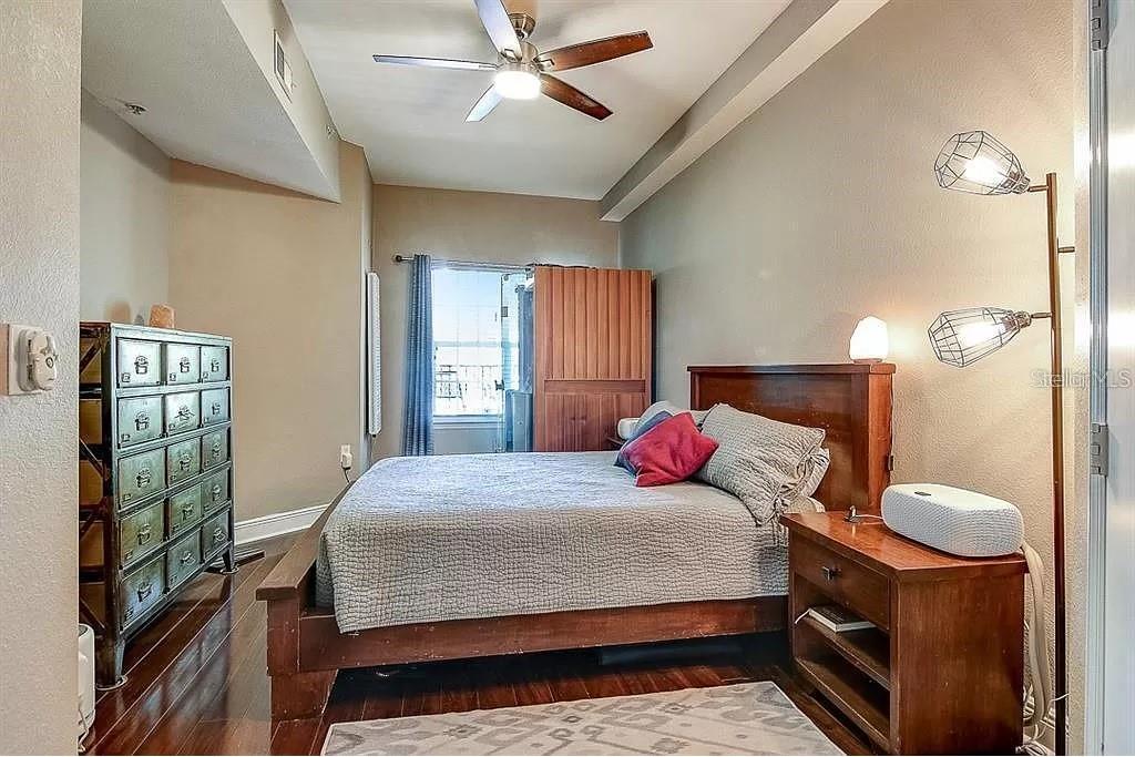 A bedroom features a wooden bed frame, a metal dresser, and a floor lamp — 100 4TH AVENUE S UNIT 205, ST PETERSBURG, FL